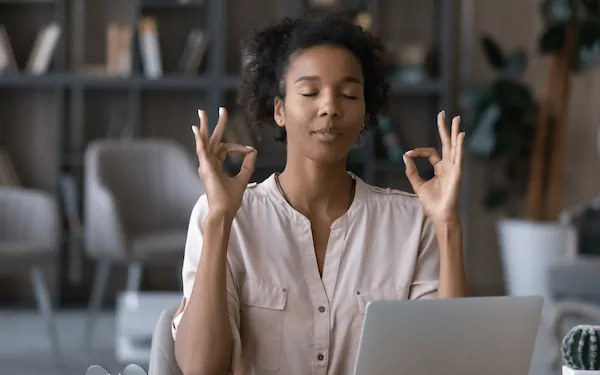 Femme méditant devant un ordinateur portable.