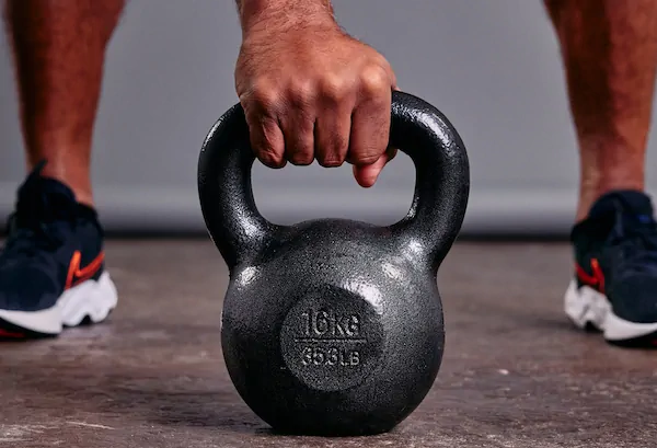 Main tenant kettlebell de 16 kg au sol.